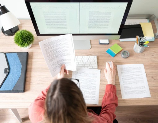 Woman sitting at desk with papers around her