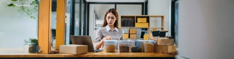 Woman standing behind counter with laptop and found containers.