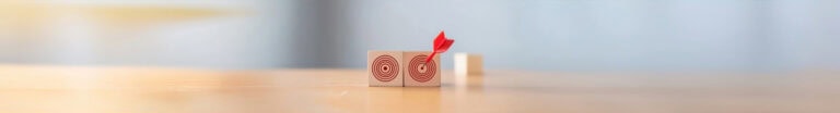 Two blocks with red targets painted on them. A dart is in the bullseye of the right block.