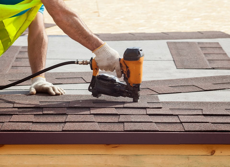 Roofer Installing Asphalt Shingles With Nail Gun